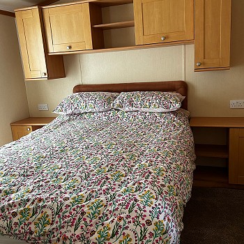 Close view of the double with flowery bedding inside the green Swift Mosell caravan